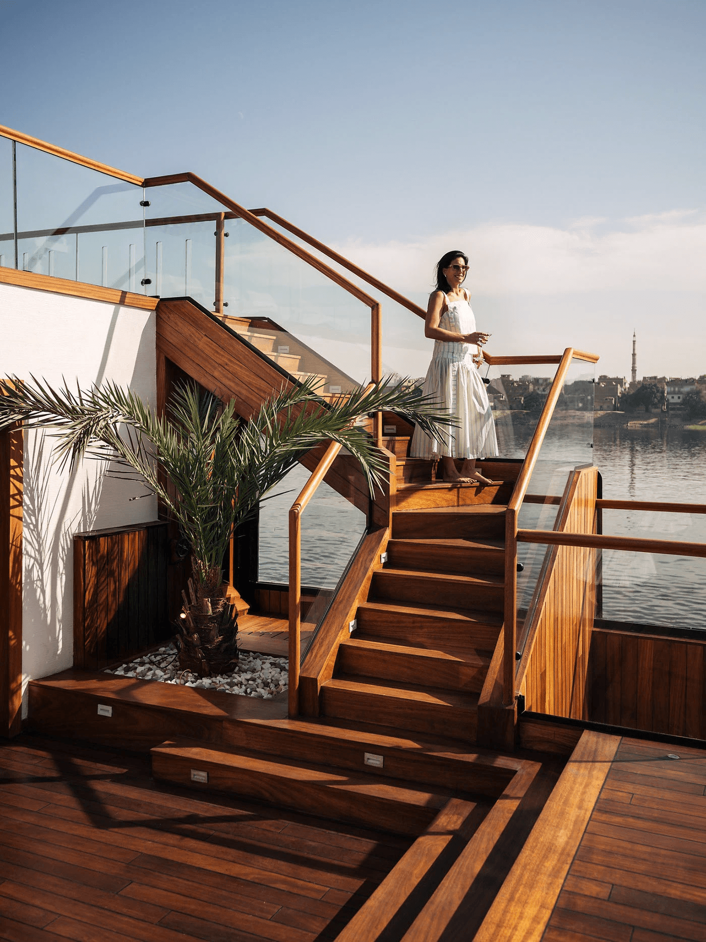 Traveller in a white dress on the wooden deck of a river cruiser