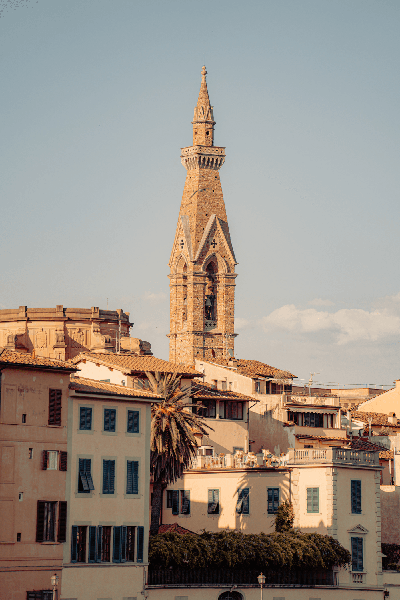Bell tower rising over sunlit rooftops in Florence